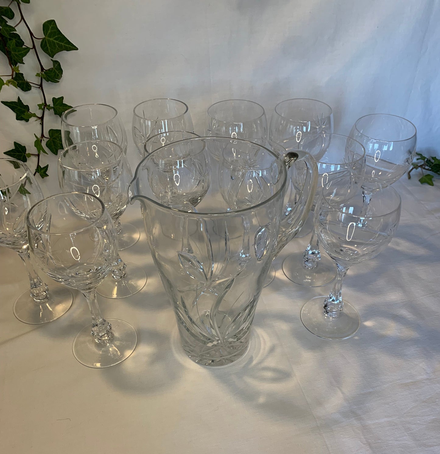 Vintage crystal table set with 6 wine goblets, 6 water goblets, and matching pitcher featuring raised floral pattern – clear glass in perfect condition.