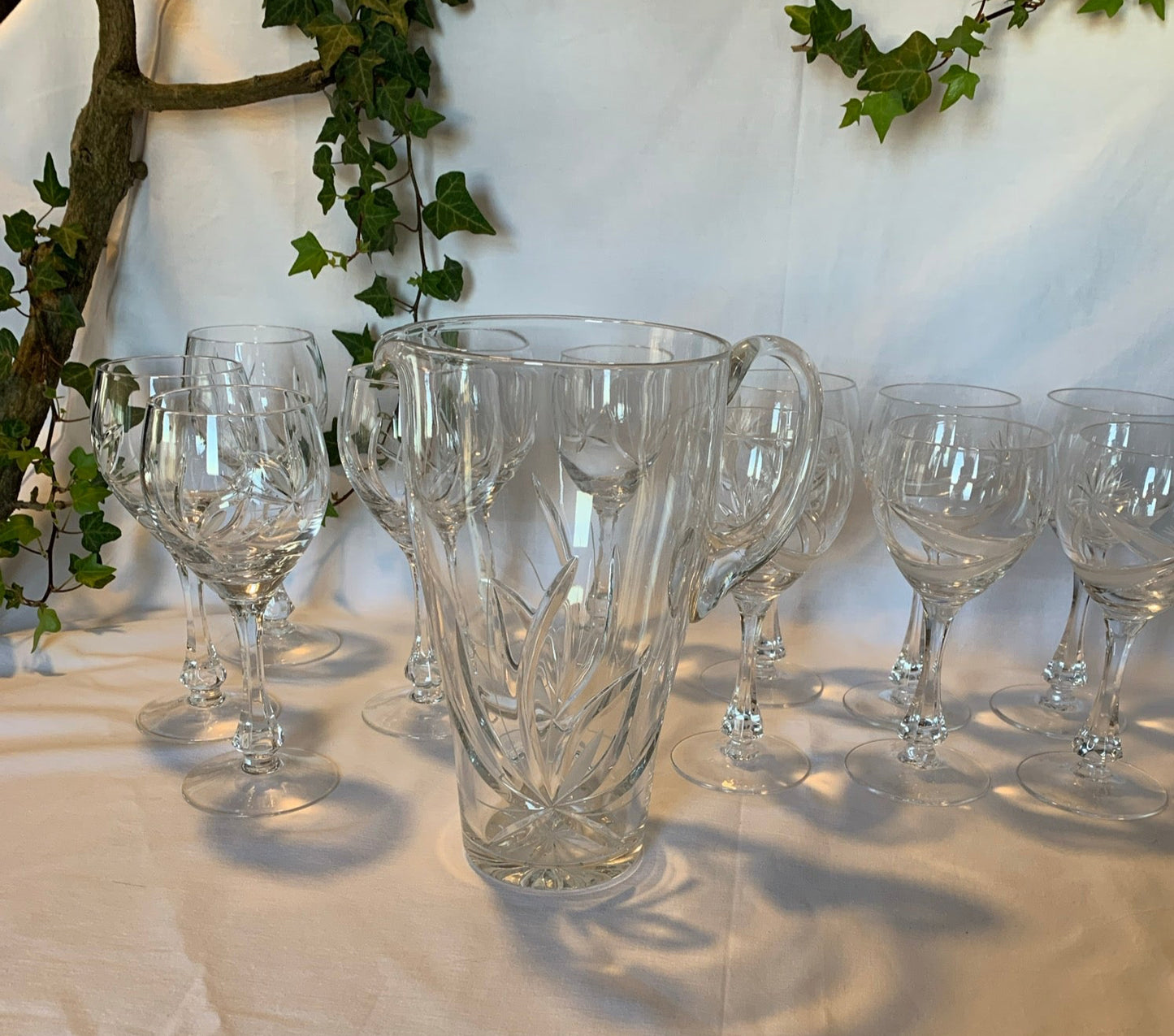 Vintage crystal table set with 6 wine goblets, 6 water goblets, and matching pitcher featuring raised floral pattern – clear glass in perfect condition.