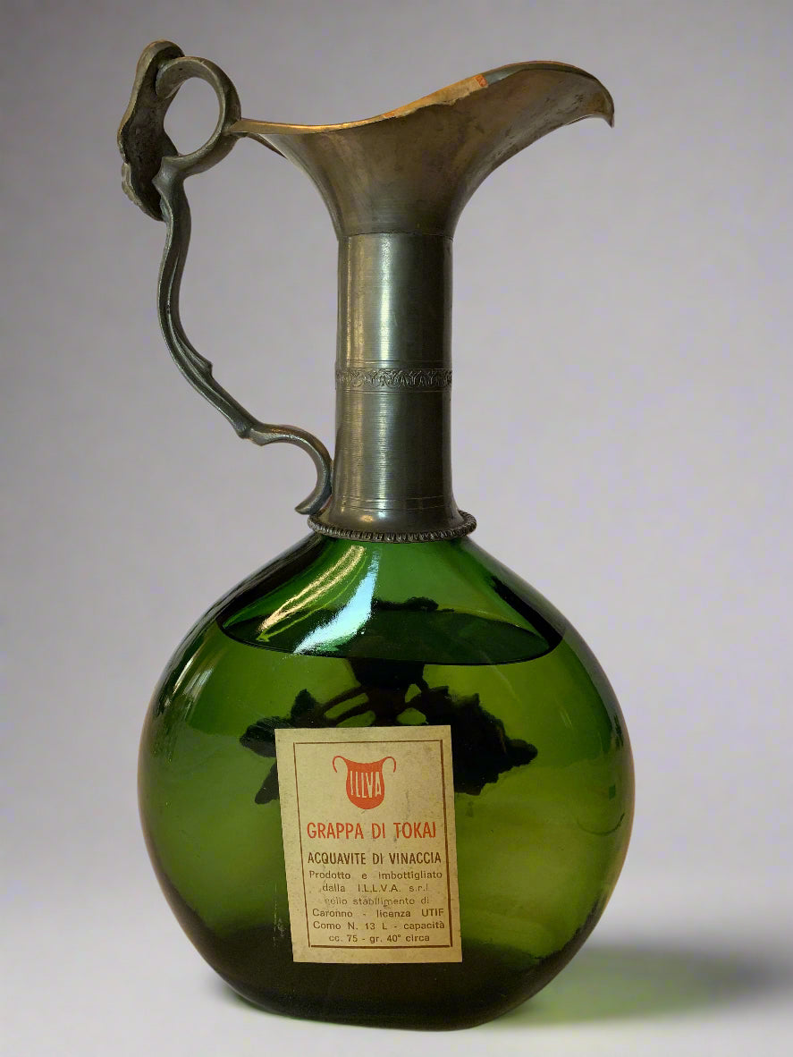 Vintage Tokai grappa bottle by I.L.L.V.A. with green glass, pewter neck, spout, and grapevine detail. Original label and seal intact – 1960s/70s.