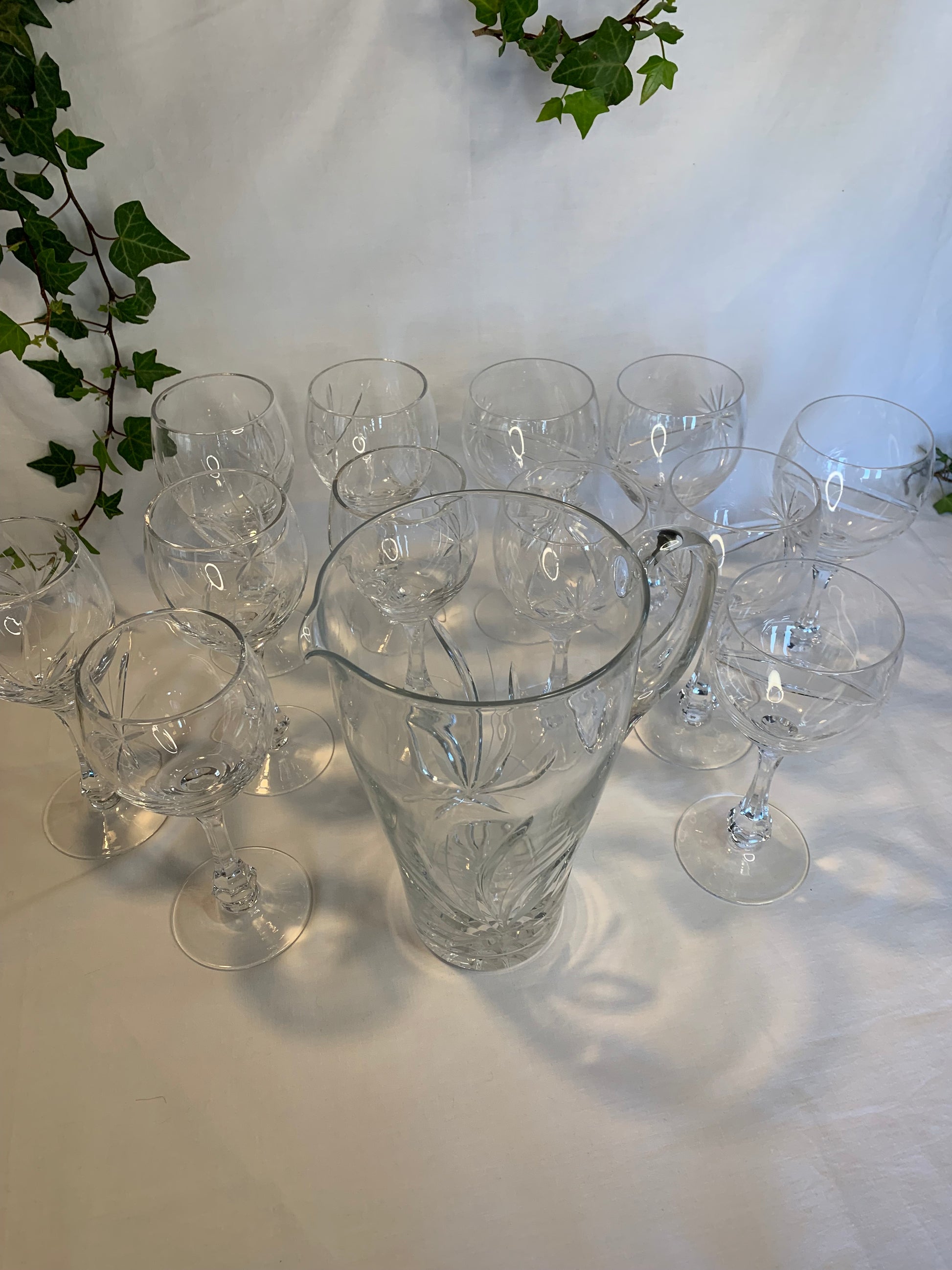 Vintage crystal table set with 6 wine goblets, 6 water goblets, and matching pitcher featuring raised floral pattern – clear glass in perfect condition.