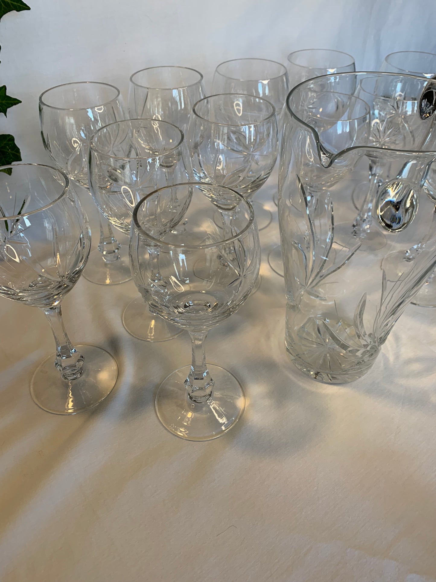 Vintage crystal table set with 6 wine goblets, 6 water goblets, and matching pitcher featuring raised floral pattern – clear glass in perfect condition.
